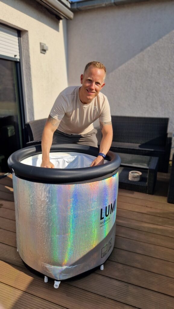 Chris am Lumi Eisbad mit silberner Isolierung, Hände im Wasser
